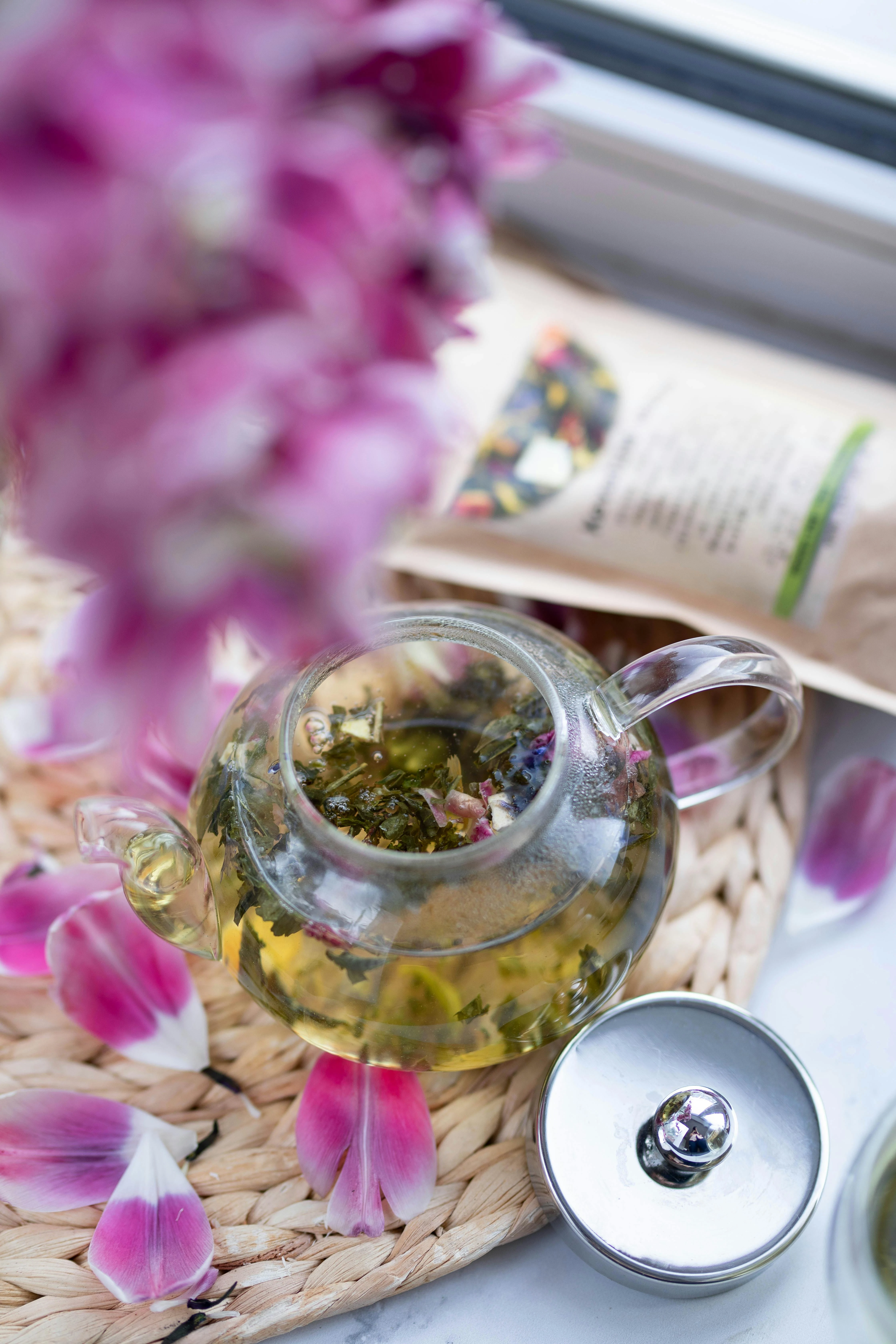 Cam bir demlikte demlenmiş açık yeşil Sencha çayı.